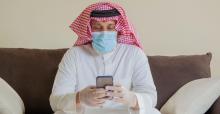 saudi-man-in-mask-and-gloves-looking-at-smartphone.jpg
